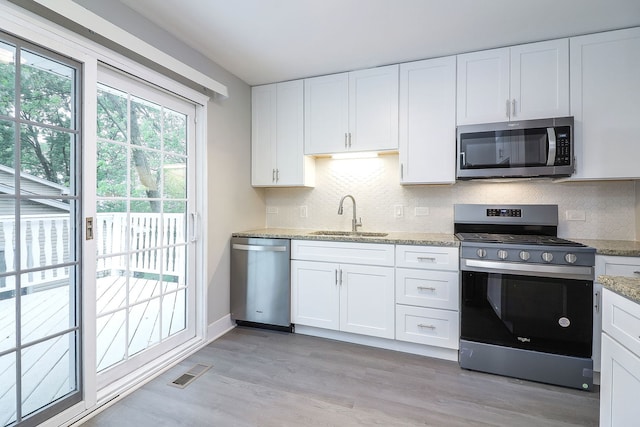 1914 Brookside Ln, Hoffman Estates, IL 60169 - kitchen with stainless steel appliances, a sink, light wood finished floors, white cabinets, and decorative backsplash