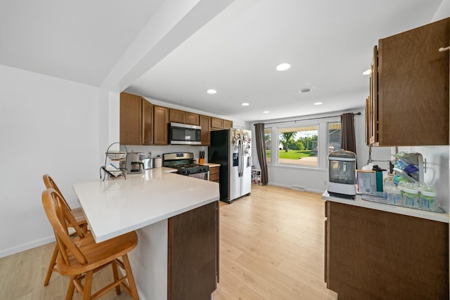 341 Cardinal Ln, Lake Holiday, IL 60552 - kitchen with stainless steel appliances, a peninsula, a kitchen bar, light countertops, and light wood finished floors