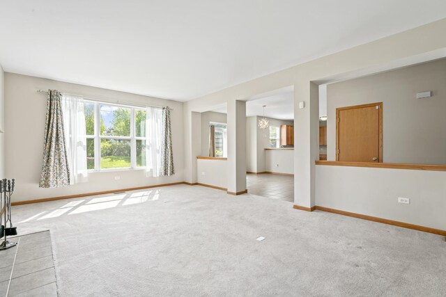 3816 Stockton Dr, Joliet, IL 60436 - unfurnished living room featuring light carpet, baseboards, and a chandelier