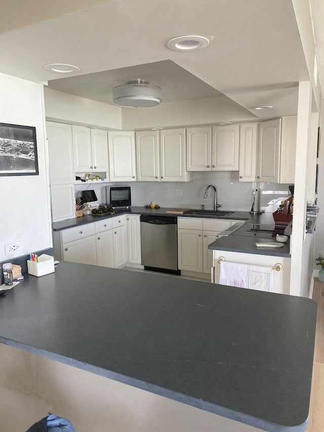 6007 N Sheridan Rd Unit 31A, Chicago, IL 60660 - kitchen with stainless steel dishwasher, a sink, dark countertops, white cabinets, and a peninsula