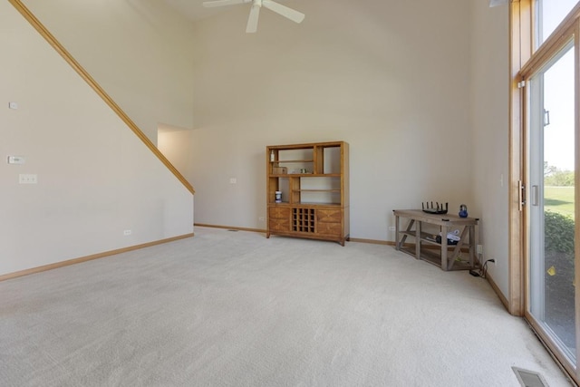 816 Adam Ln, Hampshire, IL 60140 - unfurnished living room featuring light carpet, a high ceiling, a ceiling fan, baseboards, and stairs