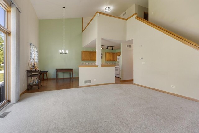 816 Adam Ln, Hampshire, IL 60140 - unfurnished living room with high vaulted ceiling, light carpet, a chandelier, and baseboards