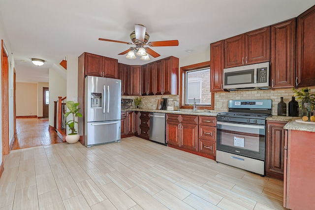 5352 N Neva Ave, Chicago, IL 60656 - kitchen featuring appliances with stainless steel finishes, a ceiling fan, tasteful backsplash, a sink, and light stone counters