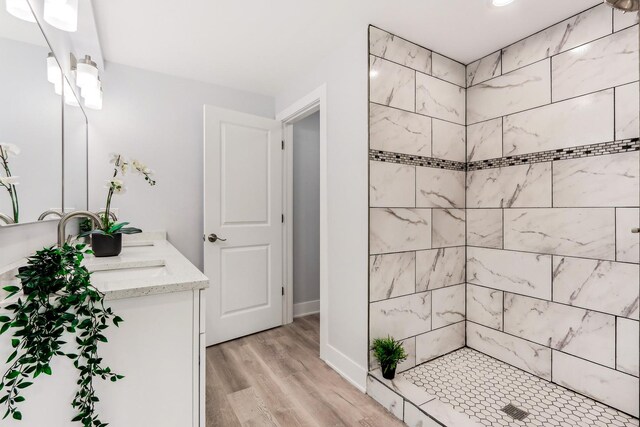 337 W 106th Pl, Chicago, IL 60628 - bathroom featuring wood finished floors, a tile shower, double vanity, and baseboards