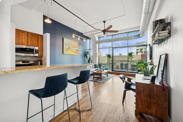 1224 W Van Buren Ave Unit 416, Chicago, IL 60607 - kitchen with stainless steel appliances, brown cabinets, wood finished floors, a ceiling fan, and a breakfast bar area