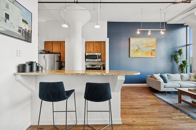 1224 W Van Buren Ave Unit 416, Chicago, IL 60607 - kitchen featuring stainless steel appliances, brown cabinets, a kitchen breakfast bar, light wood-style flooring, and a peninsula