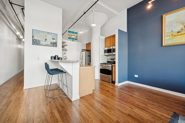 1224 W Van Buren Ave Unit 416, Chicago, IL 60607 - kitchen featuring stainless steel appliances, track lighting, brown cabinetry, a breakfast bar, and a peninsula
