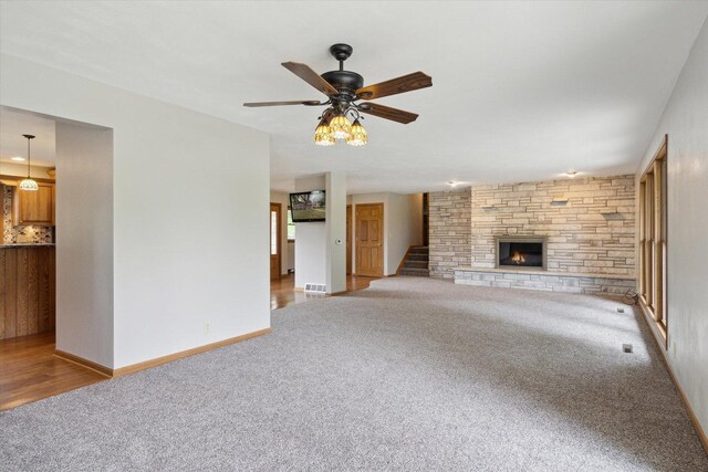 717 S Kennedy St, Shannon, IL 61078 - unfurnished living room with carpet flooring, a stone fireplace, stairway, a ceiling fan, and baseboards