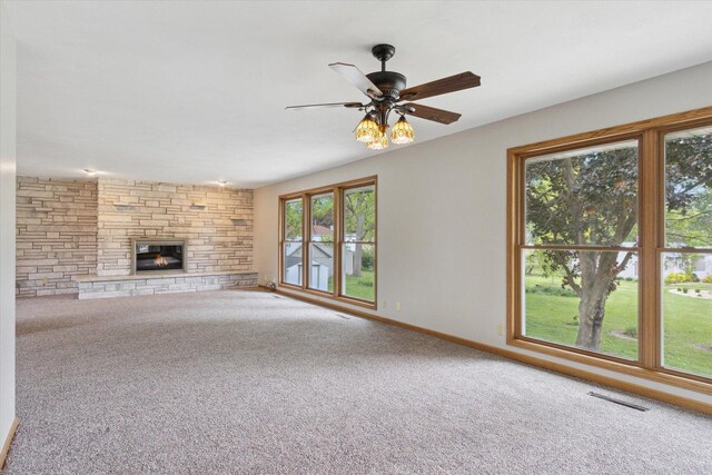 717 S Kennedy St, Shannon, IL 61078 - unfurnished living room with carpet flooring, a stone fireplace, a ceiling fan, and baseboards