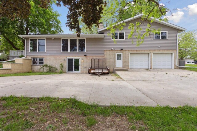 717 S Kennedy St, Shannon, IL 61078 - split level home featuring an attached garage, concrete driveway, brick siding, and a chimney