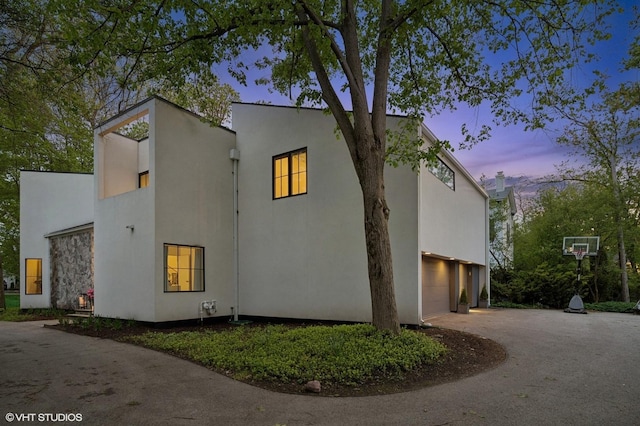 938 Old Green Bay Rd, Winnetka, IL 60093 - property exterior at dusk with a garage, asphalt driveway, and stucco siding