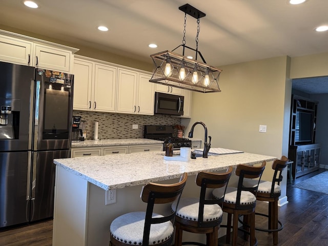 1401 Clement St, Joliet, IL 60435 - kitchen featuring appliances with stainless steel finishes, dark wood-style floors, recessed lighting, backsplash, and an island with sink