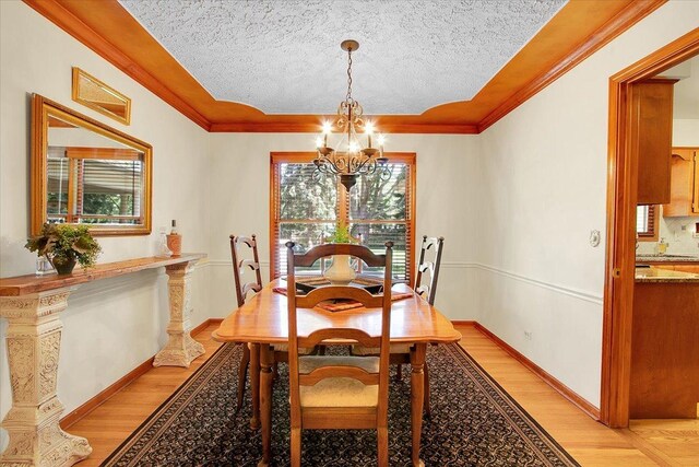 2551 Doncaster Dr, Aurora, IL 60504 - dining space featuring a chandelier, light wood finished floors, a textured ceiling, ornamental molding, and baseboards