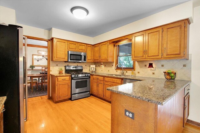 2551 Doncaster Dr, Aurora, IL 60504 - kitchen with appliances with stainless steel finishes, a peninsula, a sink, light wood finished floors, and brown cabinetry