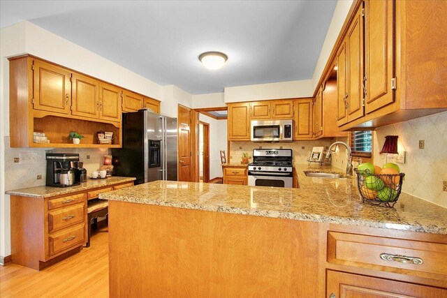 2551 Doncaster Dr, Aurora, IL 60504 - kitchen featuring appliances with stainless steel finishes, a sink, light wood-style floors, backsplash, and a peninsula