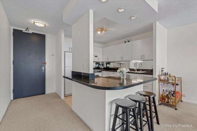 405 N Wabash Ave Unit 2314, Chicago, IL 60611 - kitchen featuring light carpet, a sink, dark countertops, a breakfast bar, and white cabinetry