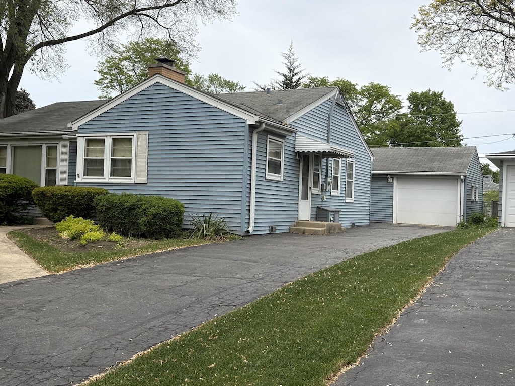 159 S Brockway St, Palatine, IL 60067 - view of front facade with a chimney, an outdoor structure, a garage, and a shingled roof