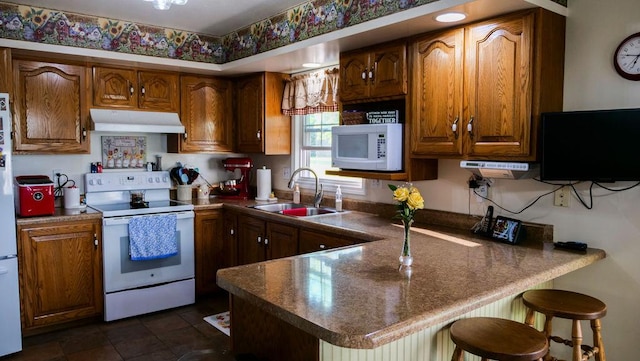 29 N Deer Lk N, Villa Grove, IL 61956 - kitchen with white appliances, under cabinet range hood, a sink, a peninsula, and brown cabinets