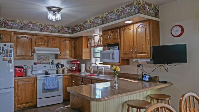 29 N Deer Lk N, Villa Grove, IL 61956 - kitchen featuring white appliances, a sink, brown cabinetry, and under cabinet range hood