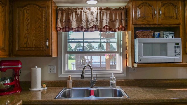 29 N Deer Lk N, Villa Grove, IL 61956 - kitchen with a sink, white microwave, healthy amount of natural light, and brown cabinetry