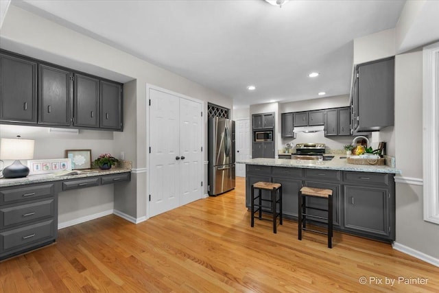 39W889 Deer Run Dr, Saint Charles, IL 60175 - kitchen with stainless steel appliances, under cabinet range hood, a peninsula, baseboards, and light wood-style floors