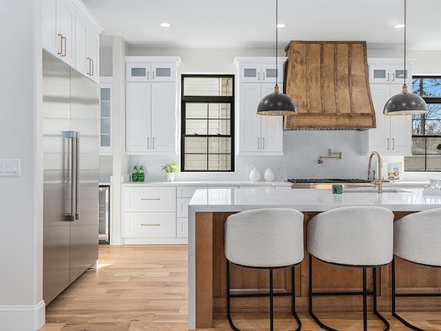 223 Center St, Naperville, IL 60540 - kitchen featuring stainless steel built in refrigerator, backsplash, glass insert cabinets, light wood-type flooring, and recessed lighting