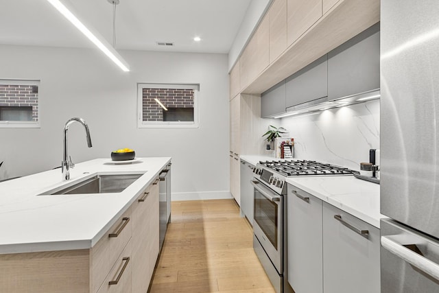 4906 N Kenmore Ave Unit 2S, Chicago, IL 60640 - kitchen with stainless steel appliances, a sink, modern cabinets, light wood finished floors, and light stone countertops