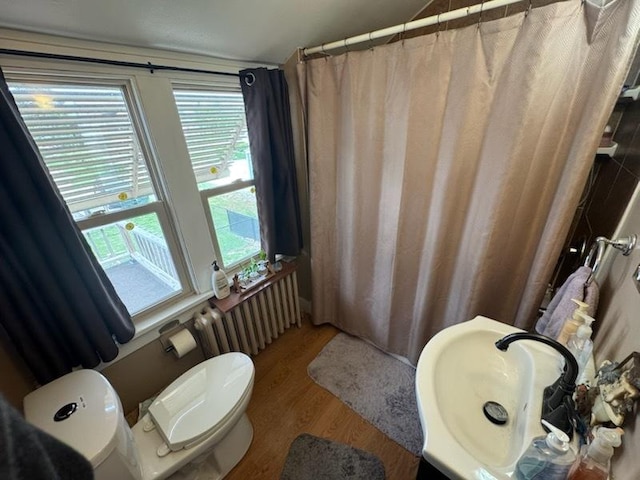 309 11th Ave, Sterling, IL 61081 - full bath featuring radiator heating unit, wood finished floors, toilet, a sink, and a shower with curtain