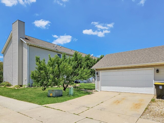 1409 Hull St, Normal, IL 61761 - view of side of home featuring a chimney, a lawn, a garage, and a shingled roof