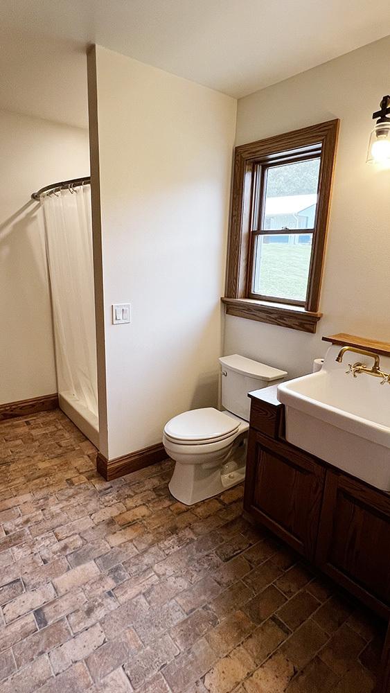 15501 Bishop Rd, Morrison, IL 61270 - full bath featuring brick flooring, toilet, a shower with shower curtain, vanity, and baseboards