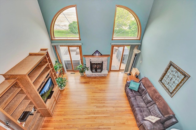 8702 Bally Castle Ln, Tinley Park, IL 60487 - living room featuring a brick fireplace, a towering ceiling, wood finished floors, and healthy amount of natural light