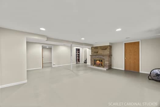 275 E Division St, Villa Park, IL 60181 - unfurnished living room featuring a brick fireplace, baseboards, concrete flooring, and recessed lighting