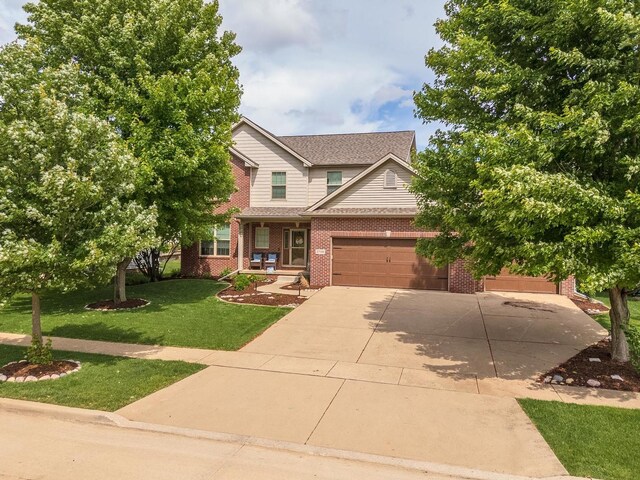 1710 Fraser Dr, Normal, IL 61761 - view of front of home with concrete driveway, a front yard, brick siding, an attached garage, and a porch