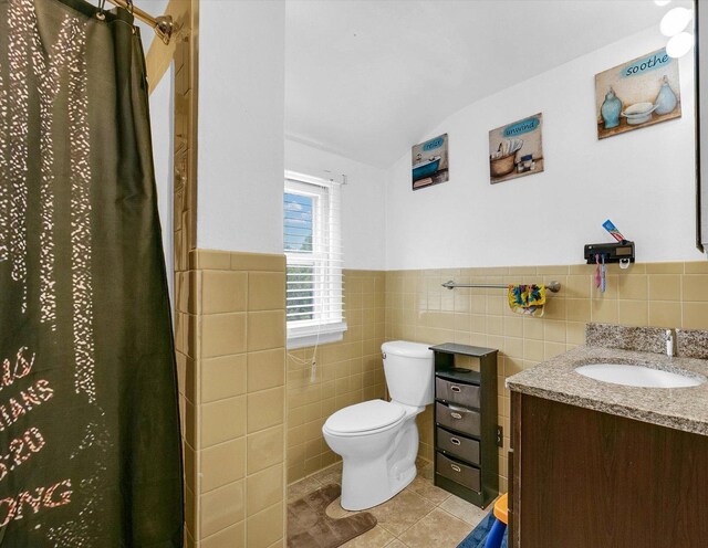 1117 W Springfield Ave, Champaign, IL 61821 - bathroom featuring lofted ceiling, tile walls, vanity, toilet, and tile patterned floors