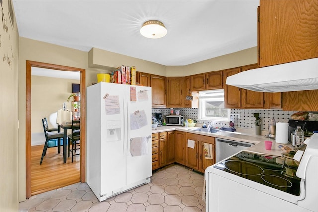 1117 W Springfield Ave, Champaign, IL 61821 - kitchen featuring stainless steel appliances, brown cabinetry, a sink, backsplash, and light countertops