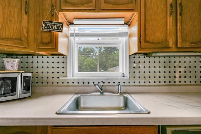 1117 W Springfield Ave, Champaign, IL 61821 - kitchen with stainless steel microwave, light countertops, a sink, and decorative backsplash