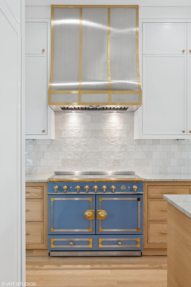 2014 N Winchester Ave, Chicago, IL 60614 - kitchen featuring range, wall chimney exhaust hood, white cabinetry, backsplash, and light wood finished floors