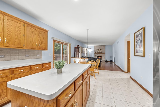 2048 Westbury Dr, Woodridge, IL 60517 - kitchen with decorative backsplash, a brick fireplace, light countertops, open floor plan, and brown cabinetry