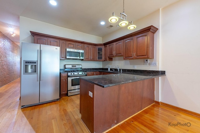 4137 S Prairie Ave Unit 3, Chicago, IL 60653 - kitchen featuring appliances with stainless steel finishes, a peninsula, light wood-style flooring, a sink, and dark stone countertops