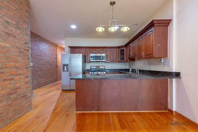 4137 S Prairie Ave Unit 3, Chicago, IL 60653 - kitchen featuring stainless steel appliances, a peninsula, brick wall, light wood-style floors, and glass insert cabinets