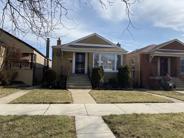 10153 S Saint Lawrence Ave, Chicago, IL 60628 - view of front of house with brick siding, a front yard, and a chimney