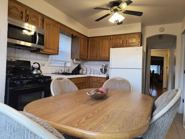 10153 S Saint Lawrence Ave, Chicago, IL 60628 - kitchen featuring stainless steel microwave, black range with gas stovetop, freestanding refrigerator, tasteful backsplash, and light countertops
