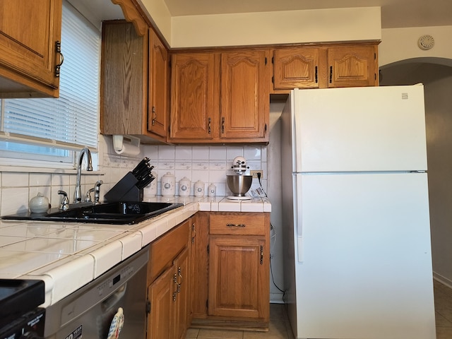 10153 S Saint Lawrence Ave, Chicago, IL 60628 - kitchen featuring freestanding refrigerator, dishwasher, tile countertops, backsplash, and range