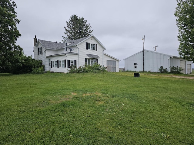 23018 Freeport Rd, Sterling, IL 61081 - rear view of house featuring a chimney, a lawn, a pole building, and an outbuilding