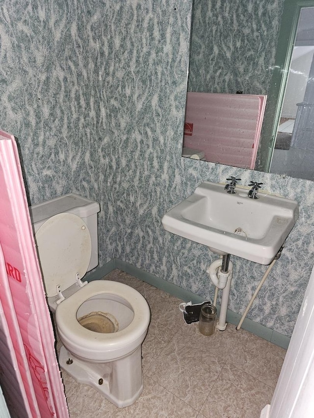 23018 Freeport Rd, Sterling, IL 61081 - half bathroom with wallpapered walls, toilet, and baseboards