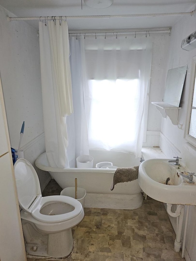 23018 Freeport Rd, Sterling, IL 61081 - bathroom with stone finish flooring, a bath, toilet, and a sink