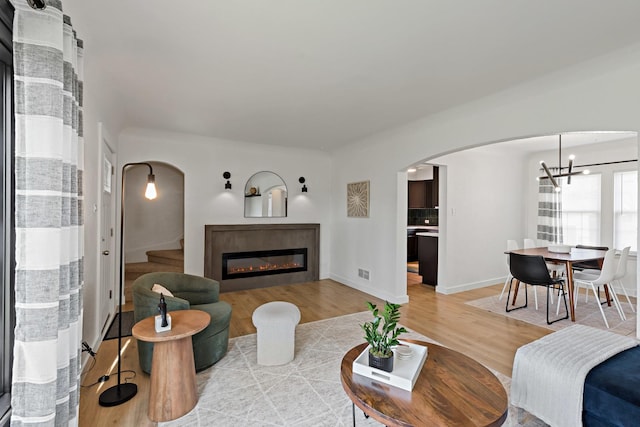 3634 177th St, Lansing, IL 60438 - living room featuring arched walkways, light wood-style floors, a glass covered fireplace, and stairway