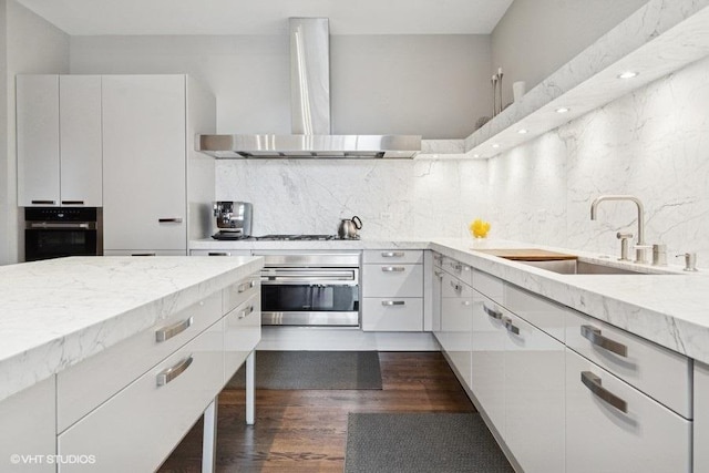 1733 S Prairie Ave, Chicago, IL 60616 - kitchen with stainless steel oven, wall chimney exhaust hood, black oven, a sink, and backsplash