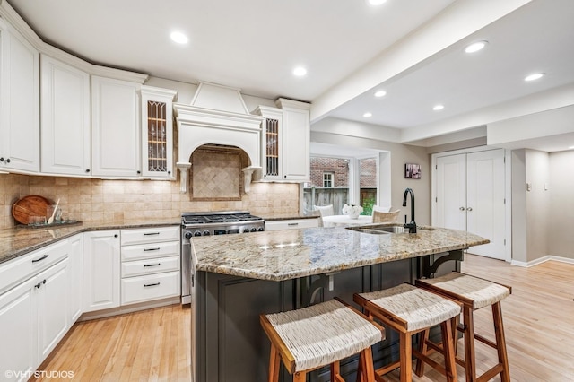 350 Elder Ln, Winnetka, IL 60093 - kitchen with high end stainless steel range, a kitchen breakfast bar, decorative backsplash, light wood finished floors, and white cabinetry