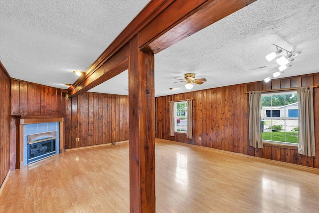 404 S Neal St, Camargo, IL 61919 - unfurnished living room with a textured ceiling, light wood-style floors, wooden walls, a tile fireplace, and ceiling fan